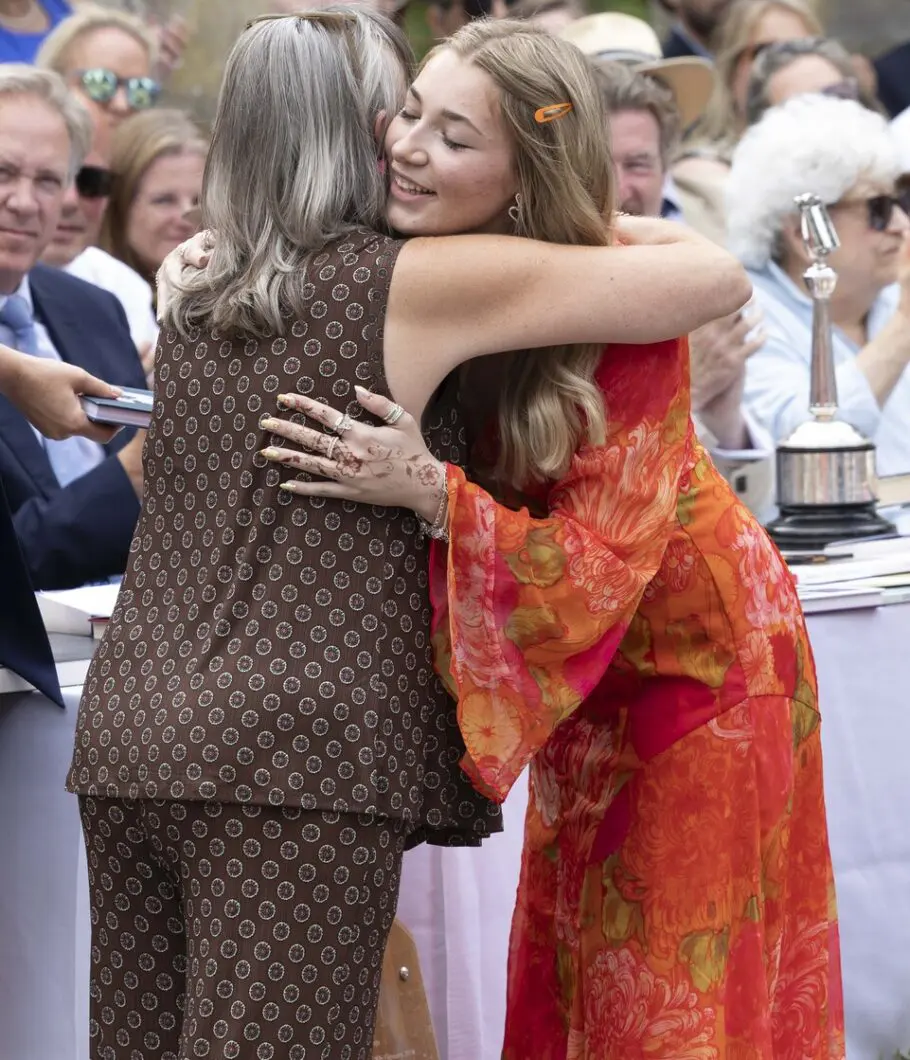 2 individuals hugging while people clap in the background